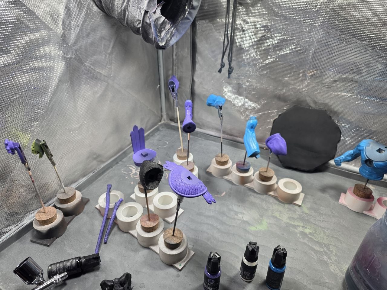 Skeletor statue parts separated on rods during the purple and blue paint stage.