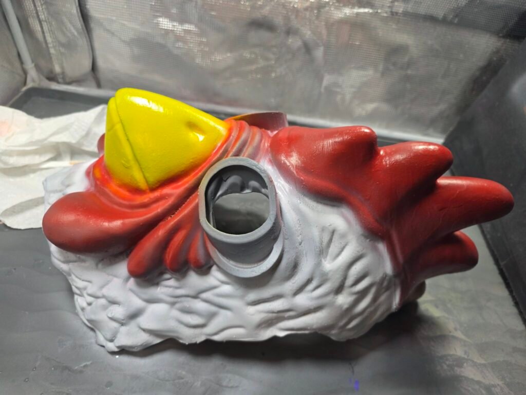 Payday 2 chicken mask with first coat of paint — red comb and yellow beak blocked in, feathers in white primer
